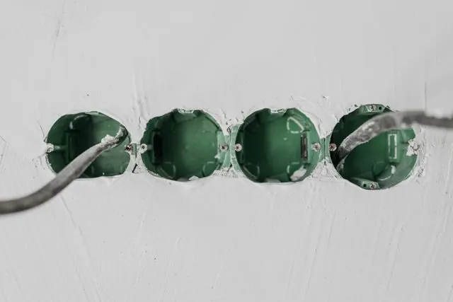 Boîtiers d'encastrement verts posés dans un mur en construction avec câbles en attente