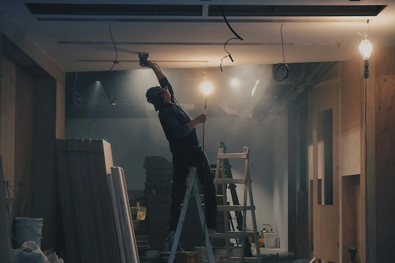 Électricien travaillant sur le câblage en plafond lors de la rénovation électrique d'une maison ancienne